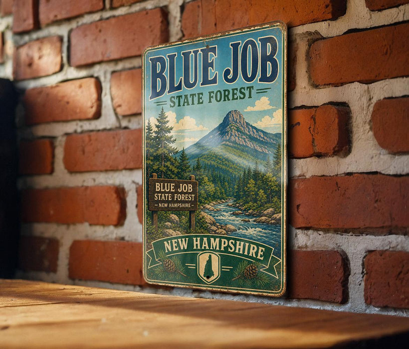 A vintage metal sign for the Blue Job State Forest in New Hampshire, featuring a scenic mountain landscape and a sign indicating the location.