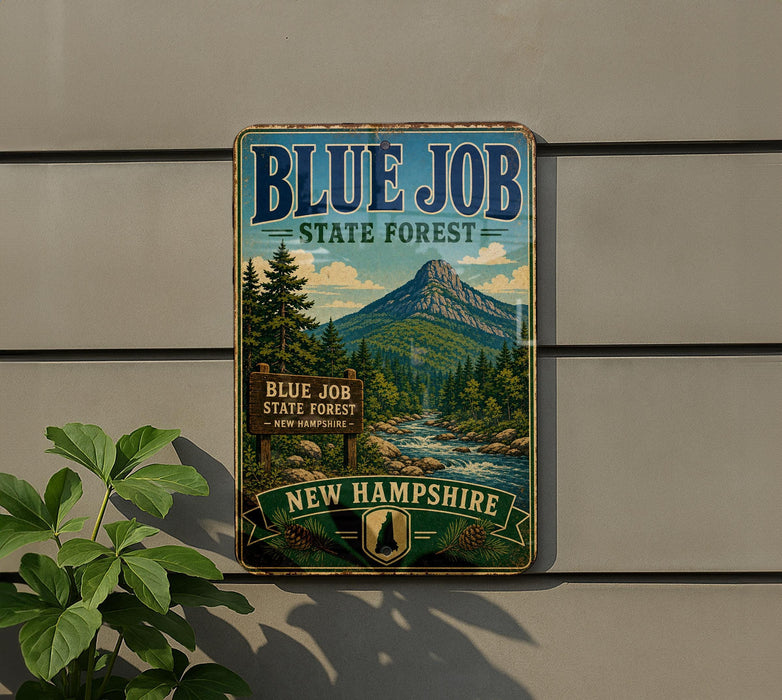 A vintage-style metal sign for the Blue Job State Forest in New Hampshire, featuring a scenic mountain landscape and pine trees.
