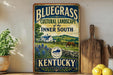 A vintage-style sign advertising the Bluegrass Cultural Landscape of the Inner South in Kentucky, featuring a farm scene with a horse and blue flowers.