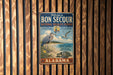 a vintage metal sign with a coastal theme, hanging on a wooden wall.