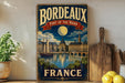 A vintage-style sign for Bordeaux, France, featuring a cityscape with a moon and a boat, along with the text "BORDEAUX PORT OF THE MOON FRANCE".