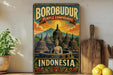 A vintage-style poster of Borobudur Temple compounds in Indonesia, featuring a Buddha statue in the foreground and a mountainous landscape in the background.