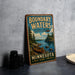 A vintage-style metal sign advertising Boundary Waters, a Minnesota wilderness area, with a canoe and a scenic lake landscape.