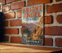 A vintage-style metal sign for the Bright Angel Trail in Arizona, featuring a scenic illustration of a hiker on a trail surrounded by mountains.
