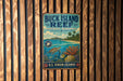 A vintage metal sign for Buck Island Reef, a National Monument in the U.S. Virgin Islands, featuring a tropical beach scene with a turtle, palm trees, and coral.