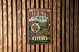 A vintage-style metal sign for the Buckeye Trail in Ohio, featuring a scenic illustration of a forest and mountains.