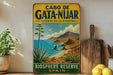 A vintage-style sign for the Gata-Nijar Reserve in Biosphere, Spain, featuring a scenic landscape with mountains, a beach, and a palm tree.