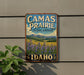 A vintage-style sign for Camas Prairie, a cultural landscape in Idaho, featuring a scenic landscape with mountains and wildflowers.