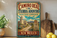 A vintage-style metal sign for "Caminos Real de Tierra Adentro Heritage Corridor" in New Mexico, featuring a desert landscape with a church and a cross.