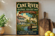a vintage-style sign for the Cane River National Heritage Area in Louisiana, with a painting of a house and a boat on the water.