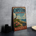 A vintage-style metal sign for Cape Cod, Massachusetts, featuring a lighthouse and a beach scene.