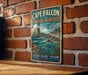 A vintage metal sign for Cape Falcon Marine Reserve, featuring an illustration of a rocky coastline, ocean, and marine life.