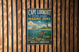 A vintage metal sign for Cape Lookout National Seashore Marine Zone, featuring an illustration of a lighthouse, a boat, and marine life, is displayed on a wooden wall.