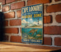 A vintage-style metal sign for Cape Lookout National Seashore Marine Zone, featuring a lighthouse and marine life, is displayed on a brick wall.