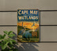 A vintage-style metal sign for Cape May Coastal Wetlands, New Jersey, featuring an illustration of a bird and a lighthouse.