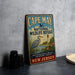 A vintage metal sign for Cape May National Wildlife Refuge, featuring an illustration of a crane and a lighthouse, is displayed on a gray countertop next to a stack of camera lenses.