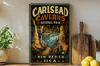 A vintage-style metal sign for Carlsbad Caves National Park in New Mexico, USA, featuring an illustration of the cave system with stalactites and stalagmites.