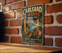 A vintage-style metal sign for Carlsbad Caves National Park, New Mexico, USA, featuring an illustration of the cave system and the park's name.