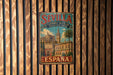 A vintage metal sign with the text "SEVILLA Catedral-Alcazar Archivo de Indias" and "ESPAÑA" is displayed on a wooden wall.