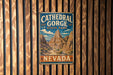 A vintage metal sign for Cathedral Gorge State Park in Nevada, featuring a scenic mountain landscape.