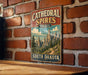 A vintage metal sign for the Cathedral Spires Trail in South Dakota is displayed on a brick wall.