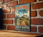 A vintage-style metal sign for the Centennial Trail in South Dakota, featuring a scenic mountain landscape and a trail winding through it.