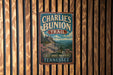 A vintage metal sign for Charlie's Bunion Trail in Tennessee, featuring a scenic mountain landscape.