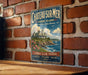 A vintage metal sign for Chateau Summer in Rhode Island, featuring a scenic coastal landscape with a house and ocean views.