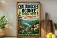 A vintage-style metal sign for the Chattahoochee Oconee National Forests in Georgia, featuring a scenic landscape with a river, mountains, and pine trees.