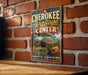 A vintage-style sign for the Cherokee Heritage Center in Oklahoma, featuring a colorful illustration of a building and a pottery wheel.