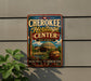 A vintage-style sign for the Cherokee Heritage Center in Oklahoma, featuring a colorful illustration of the center's architecture and surrounding landscape.