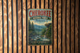 A vintage metal sign for the Cherokee National Forest in Tennessee, featuring a scenic mountain landscape with a river and pine trees.