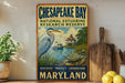 A vintage-style metal sign for Chesapeake Bay National Estuarine Research Reserve, featuring an illustration of a heron and a lighthouse, with the text "Discover, Protect, Understand Maryland".