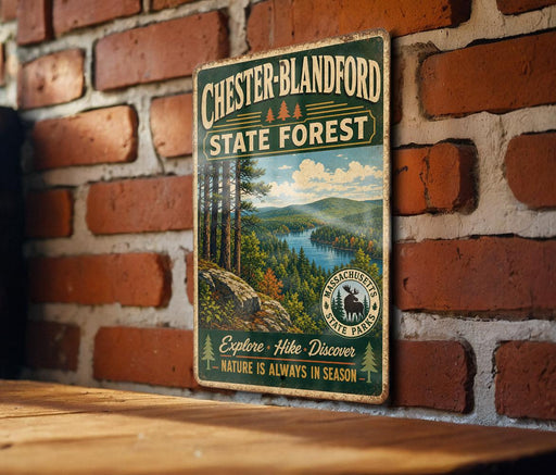 A vintage metal sign for Chester-Blandford State Forest, featuring a scenic mountain landscape with pine trees and a lake.