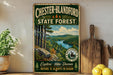 A vintage-style metal sign for Chester-Blandford State Forest, featuring a scenic landscape with pine trees, a river, and mountains.