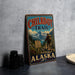 A vintage metal sign for the Chilko Trail in Alaska, featuring a hiker and mountainous landscape.