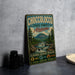 A vintage-style metal sign for Choccolocco State Forest in Alabama, featuring a scenic illustration of a mountain, river, and forest.