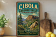 A vintage-style metal sign for the Cibola National Forest in New Mexico, featuring a scenic mountain landscape and the text "Cibola National Forest" and "New Mexico".