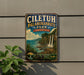 A vintage-style metal sign with text and a scenic illustration of a tropical landscape, mounted on a wall next to a plant.