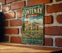 A vintage metal sign with the text "CISTERCIAN ABBEY OF FONTENAY FRANCE" and "900 YEARS OF HERITAGE PEACE - SIMPLICITY - TRADITION" is displayed on a brick wall.