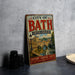 A vintage-style metal sign for the City of Bath, United Kingdom, featuring an illustration of Bath's historic architecture and a river.