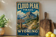 A vintage-style metal sign for the Cloud Peak Trail in Wyoming, featuring a scenic mountain landscape with a trail leading through it.