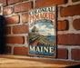 A vintage-style metal sign for the Colonial Pemaid State Historic Site in Maine, featuring a cannon and a ship on a rocky coastline.