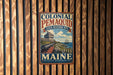 A vintage-style metal sign for the Colonial Pemaid State Historic Site in Maine, featuring a ship and a lighthouse on a wooden background.