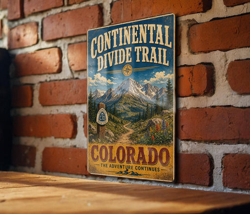 A vintage metal sign for the Continental Divide Trail in Colorado, featuring a mountain landscape and a compass rose.