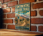 A vintage metal sign for the Continental Divide Trail in New Mexico, featuring a scenic mountain landscape and a trail marker.