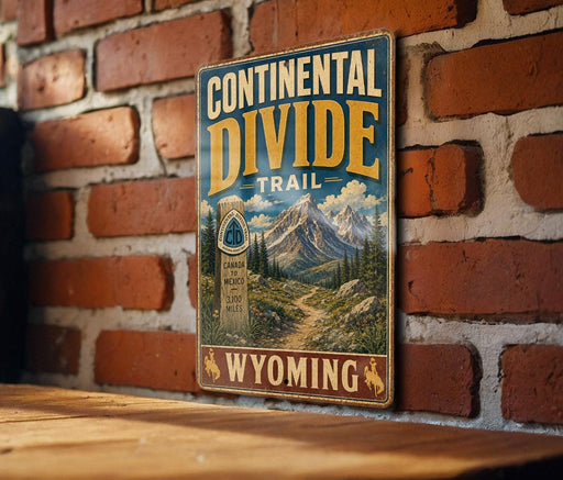 A vintage metal sign for the Continental Divide Trail in Wyoming, featuring a mountain landscape and a trail marker.