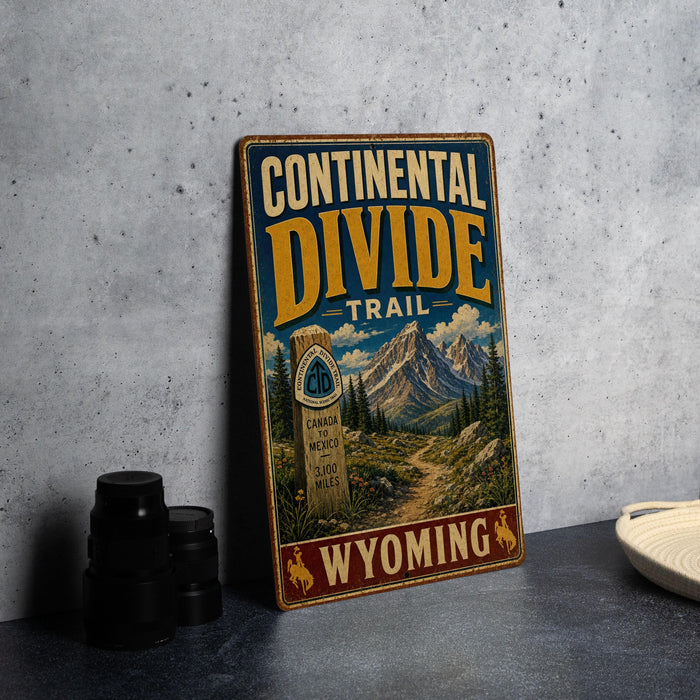 A vintage-style metal sign for the Continental Divide Trail in Wyoming, featuring a scenic mountain landscape and trail marker.