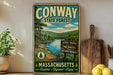 a vintage-style metal sign for the Conway State Forest in Massachusetts, with a scenic landscape of pine forests and a lake. The sign is displayed on a wooden shelf, surrounded by various kitchen utensils and a potted plant.