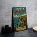 A vintage metal sign for Costa Quedbrada Park in Spain, featuring a scenic coastal landscape with cliffs and the ocean.